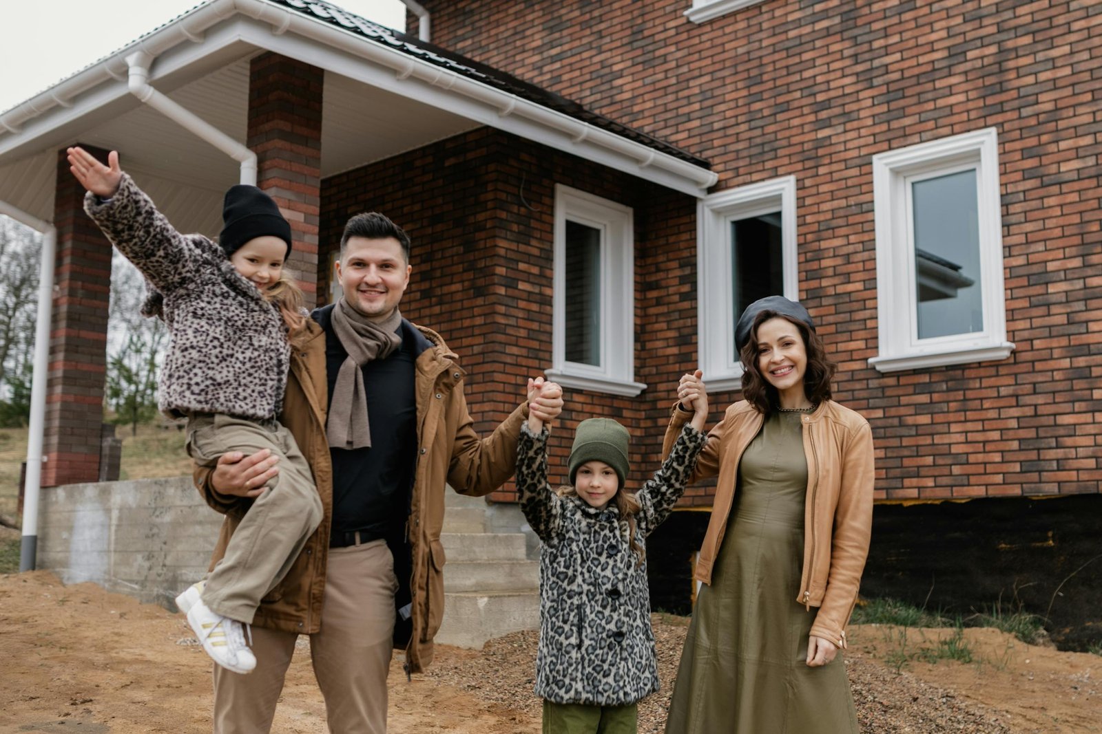 Joyful family celebrates new home purchase with smiles and warm attire.